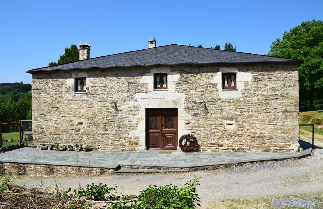 Fachada principal de piedra con puerta de madera